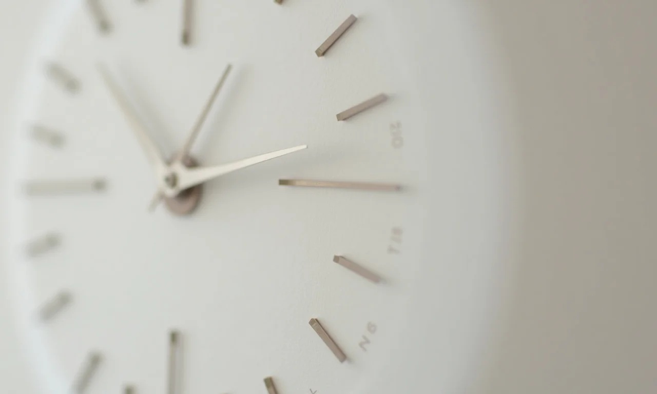 Relógio de parede com ponteiros diferenciados e design minimalista.